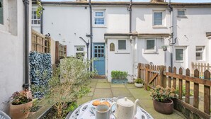 A courtyard with a table set for tea, surrounded by potted plants and a wooden fence. - 1 Bed in Eastbourne (oc-ehc24) (Eastbourne)