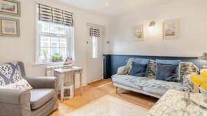 A cozy living room with a grey sofa, a patterned blue sofa, a small table with a sailboat, and a window with blinds. - 1 Bed in Eastbourne (oc-ehc24) (Eastbourne)
