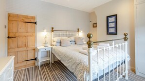 A bedroom with a bed, nightstands, a wooden door, and a framed picture on the wall. - 1 Bed in Eastbourne (oc-ehc24) (Eastbourne)