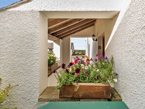 A covered outdoor area with a wooden bench, a planter with flowers, and a view of a building in the background. - 2 Bed in Wigton (oc-93463) (Ireby)