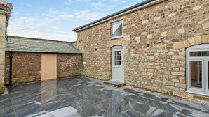 A stone building with a tiled patio, a door, and a window. - 2 Bed in Ripon (oc-94000) (Littlethorpe)