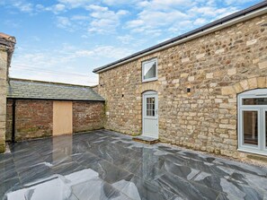 A stone building with a tiled patio, a door, and a window. - 2 Bed in Ripon (oc-94000) (Littlethorpe)