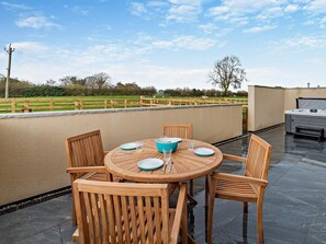 A round wooden table with chairs, a hot tub, and a view of a green field. - 2 Bed in Ripon (oc-94000) (Littlethorpe)