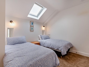 Ein Schlafzimmer mit zwei Betten, einem Dachfenster und zwei Wandleuchten.