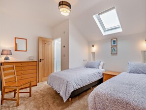 A bedroom with a skylight, a wooden wardrobe, a desk with a lamp, and a bed with patterned bedding. - 2 Bed in Ripon (oc-94000) (Littlethorpe)