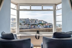 Ein Zimmer mit großem Fenster und Blick auf eine Küstenstadt.