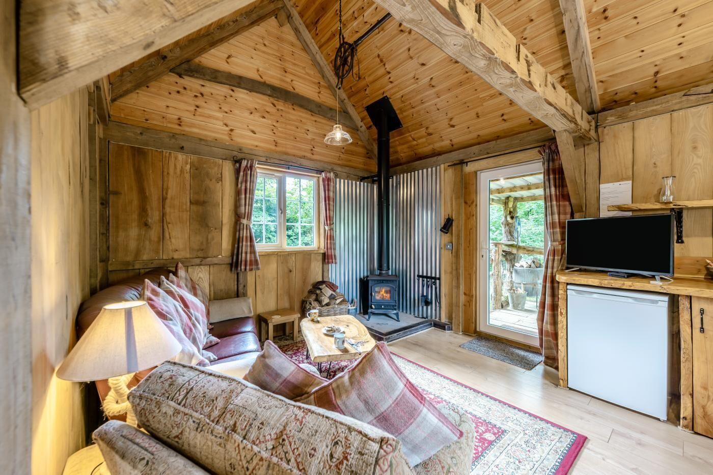 L’intérieur d’un chalet confortable, avec un canapé, une table, une cheminée et un téléviseur.