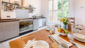 Een moderne keuken met een groot raam, houten vloer en een ontbijtgedeekte eethoek.