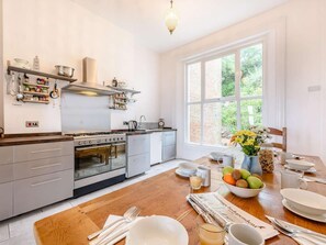 A modern kitchen with a large window, wooden flooring, and a dining area set for breakfast. - 7 Bed in St. Leonards-on-sea (oc-52620) (Hastings)