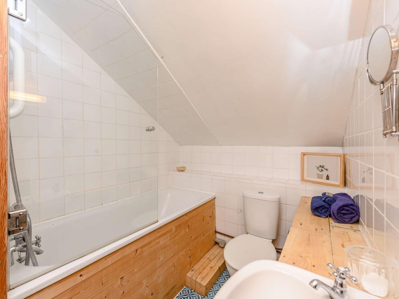A bathroom with a bathtub, toilet, and wooden vanity.