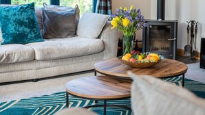 Un salon avec un canapé, une table basse ronde en bois et un vase rempli de fleurs.