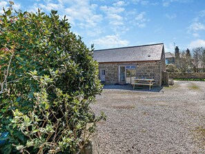 A stone building with a gravel driveway and a wooden bench. - 1 Bed in Penzance (oc-75689) (Lamorna)