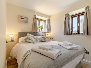A bedroom with a bed, two bedside lamps, a window with curtains, and a painting on the wall. - 1 Bed in Penzance (oc-75689) (Lamorna)