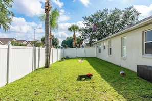 A backyard with a white fence, a palm tree, and a small bench. - Spacious 6-bedroom pool house near Disney (Kissimmee)