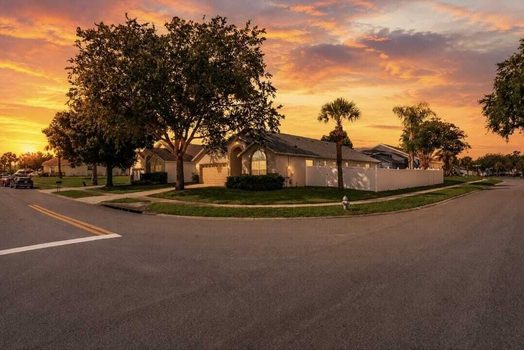 A residential street with houses, a clear sky, and a sunset.