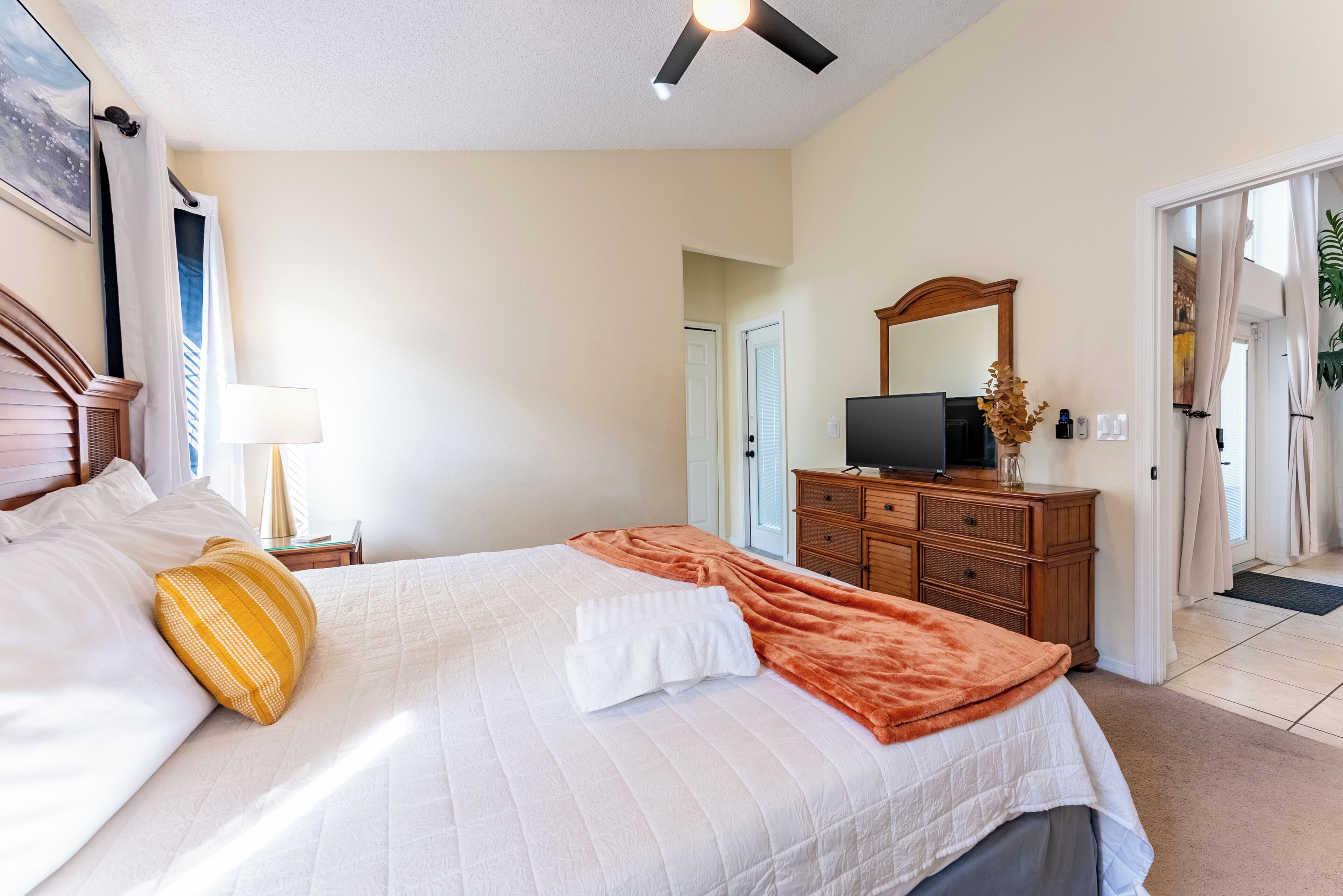 Une chambre d’hôtel comprenant un lit, une télévision, une commode et une porte donnant sur une autre pièce.
