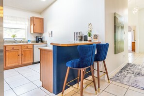 Une cuisine moderne avec un coin bar, des meubles en bois et un tabouret de bar bleu.