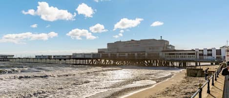 A beach with a pier and a building labeled 'Sandcastle Place.'