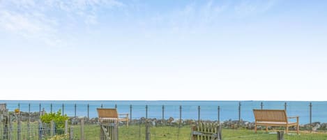 A garden with a wooden fence, benches, and a view of the sea.