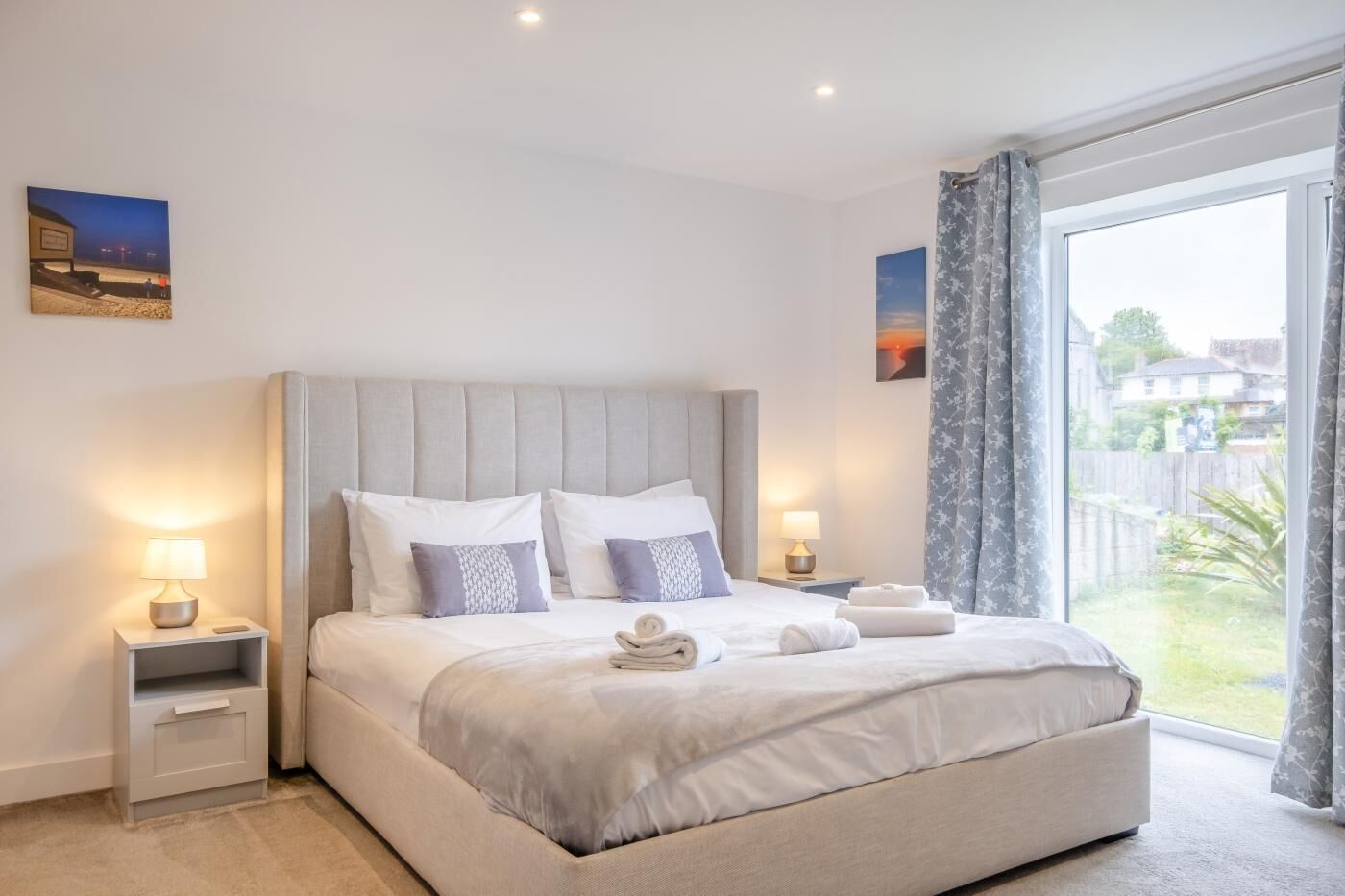 Ein modernes Schlafzimmer mit einem großen Bett, Nachttischen und Blick ins Freie.