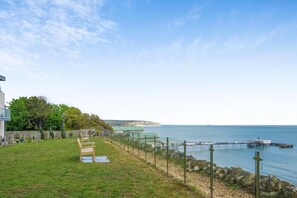 A coastal property with a grassy lawn, a wooden deck, and a view of the sea. - 2 Bed in Sandown (oc-90013) (Sandown)