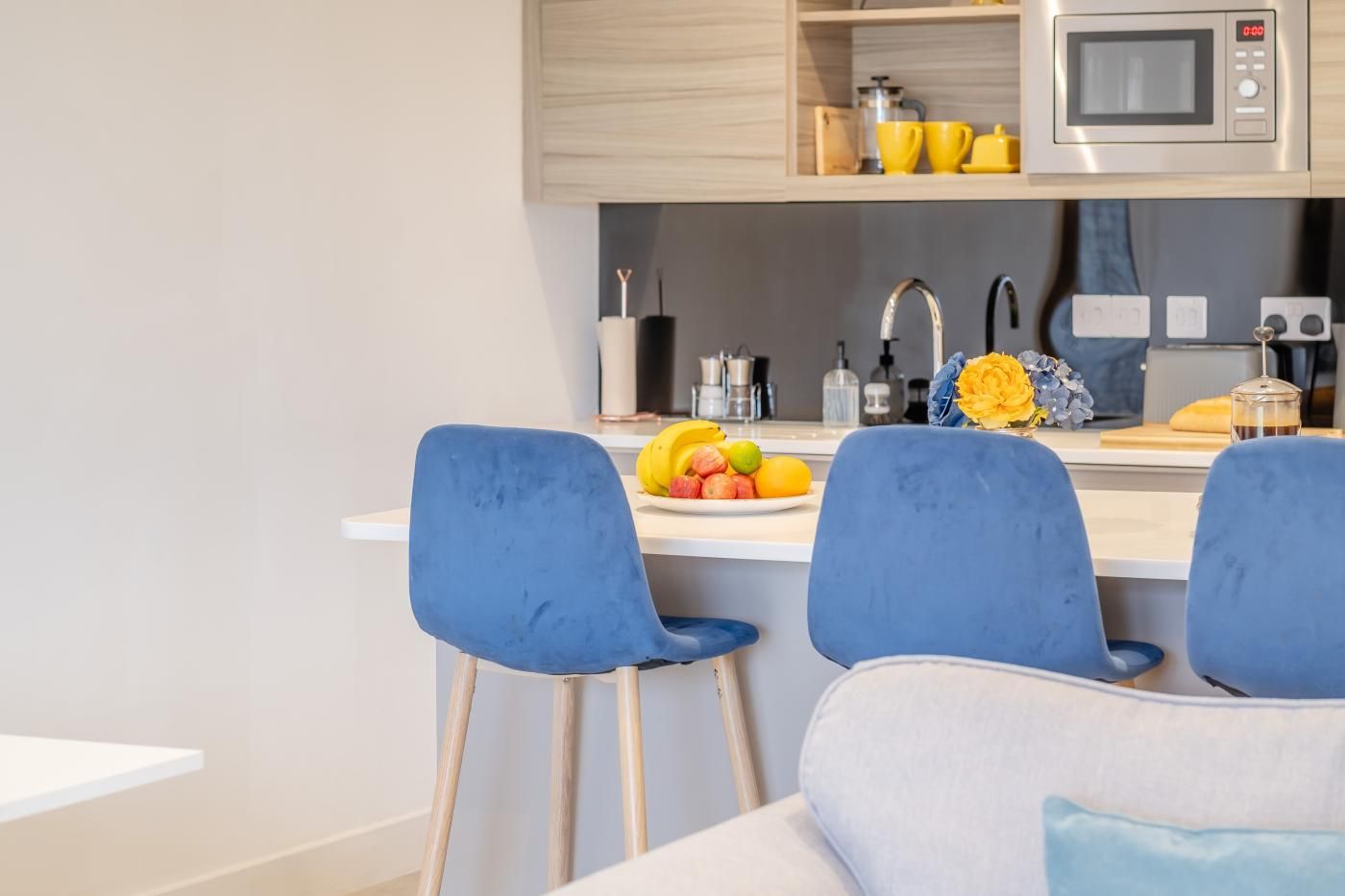 A modern kitchen with a microwave, sink, and bar stools.