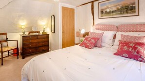 Ein Schlafzimmer mit Bett, Schminktisch, Sessel und einem Bild an der Wand.