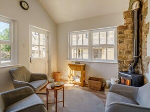 Ein gemütliches Wohnzimmer mit Kamin aus Stein, einem Holztisch und zwei Sofas.
