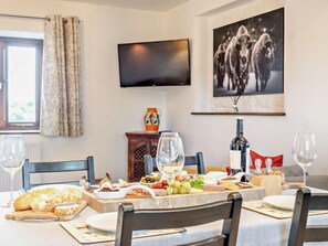 A dining area with a table set for a meal, a television mounted on the wall, and a framed picture above the table. - 2 Bed in Taunton (oc-93581) (Norton Fitzwarren)