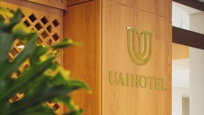 Un mostrador de recepción de madera con un logotipo y el nombre 'UAIHOTEL' en el centro.