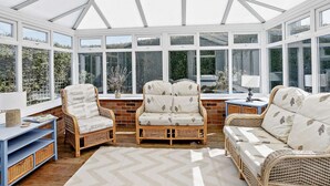 A conservatory with wicker furniture, large windows, and a ceiling fan. - 3 Bed in Mablethorpe (oc-sealc) (Mablethorpe and Sutton)