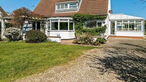 A two-story house with a sloped roof, a conservatory, and a well-maintained garden. - 3 Bed in Mablethorpe (oc-sealc) (Mablethorpe and Sutton)