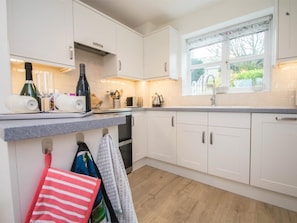 A kitchen with white cabinets, a countertop, a window, and a wooden floor. - 3 Bed in Swanage (oc-dc054) (Worth Matravers)