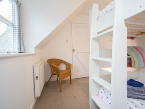 A room with a white bunk bed, a wicker chair, and a radiator. - 3 Bed in Swanage (oc-dc054) (Worth Matravers)