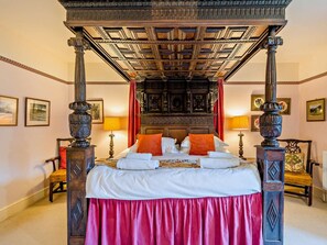 A four-poster bed with a wooden headboard, red curtains, and a red skirt on the bed. - 4 Bed in Holmrook (oc-sz158) (Eskdale)
