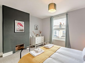 A modern bedroom with a bed, bedside tables, a dresser, a framed picture, and a window with a view. - 3 Bed in Paignton (oc-92888) (Paignton)