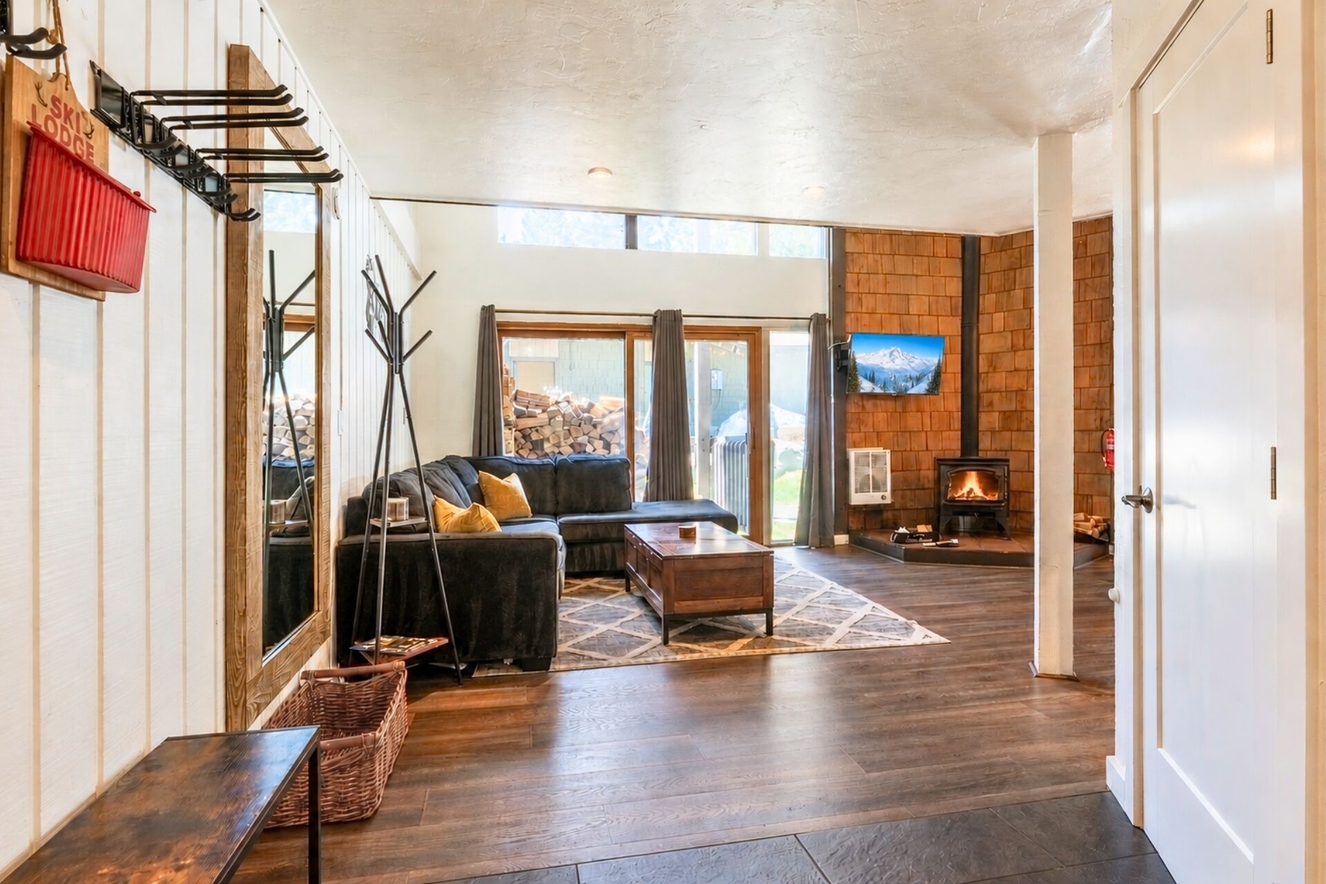 Un salon moderne avec un canapé d’angle, une cheminée et une grande fenêtre.