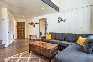 Ein Wohnzimmer mit einem Ecksofa, einem Holztisch und einem Teppich mit Muster.