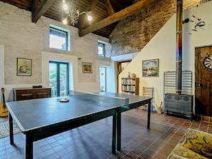 A room with a ping pong table, a dartboard, a bookshelf, a guitar, and a rustic stone wall. - 3 Bed in Abergavenny (oc-93362) (Capel-y-ffin)