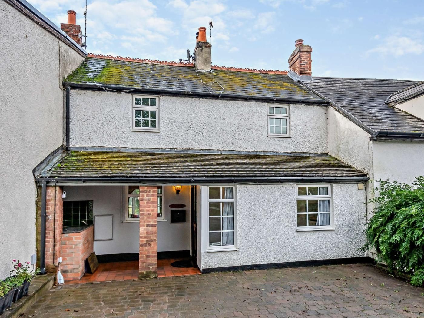 A two-story house with a small attached kitchen, a brick chimney, and a tiled roof.