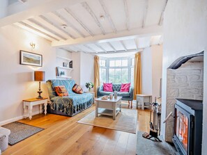 A cozy living room with a fireplace, wooden flooring, and a large window with curtains. - 2 Bed in Swindon (oc-93489) (Bishopstone)