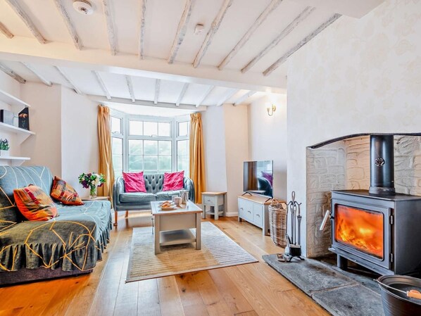 A cozy living room with a fireplace, a sofa, a coffee table, and a television.
