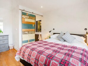 Een slaapkamer met een bed, een dressoir, een spiegel en een wand met een kleurrijk houten paneelontwerp.