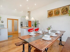 Een moderne keuken met een eethoek, een houten tafel en rode stoelen.