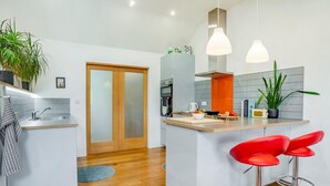 Een moderne keuken met een centraal eiland, barkrukken en hanglampen.