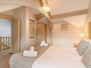 Ein Schlafzimmer mit Bett, Spiegel, Tür, einem Bild an der Wand und einer Lampe.