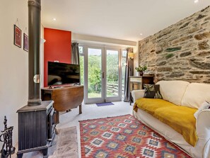 A cozy living room with a fireplace, a television, and a stone wall. - 2 Bed in Machynlleth (oc-93645) (Glaspwll)