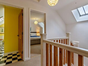 Eine Treppe führt zu einem Schlafzimmer mit einem Bett, einem Fenster und einer Deckenleuchte.