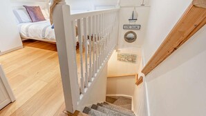 Eine Treppe mit weißer Geländer, einer Holzhandläufe und einem kleinen Teppich am Fuß.