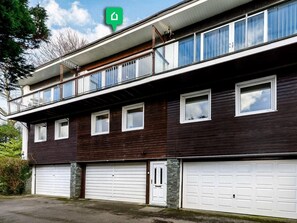 Ein zweistöckiges Gebäude mit Balkon, mehreren Fenstern und zwei Garagenzufahrten.